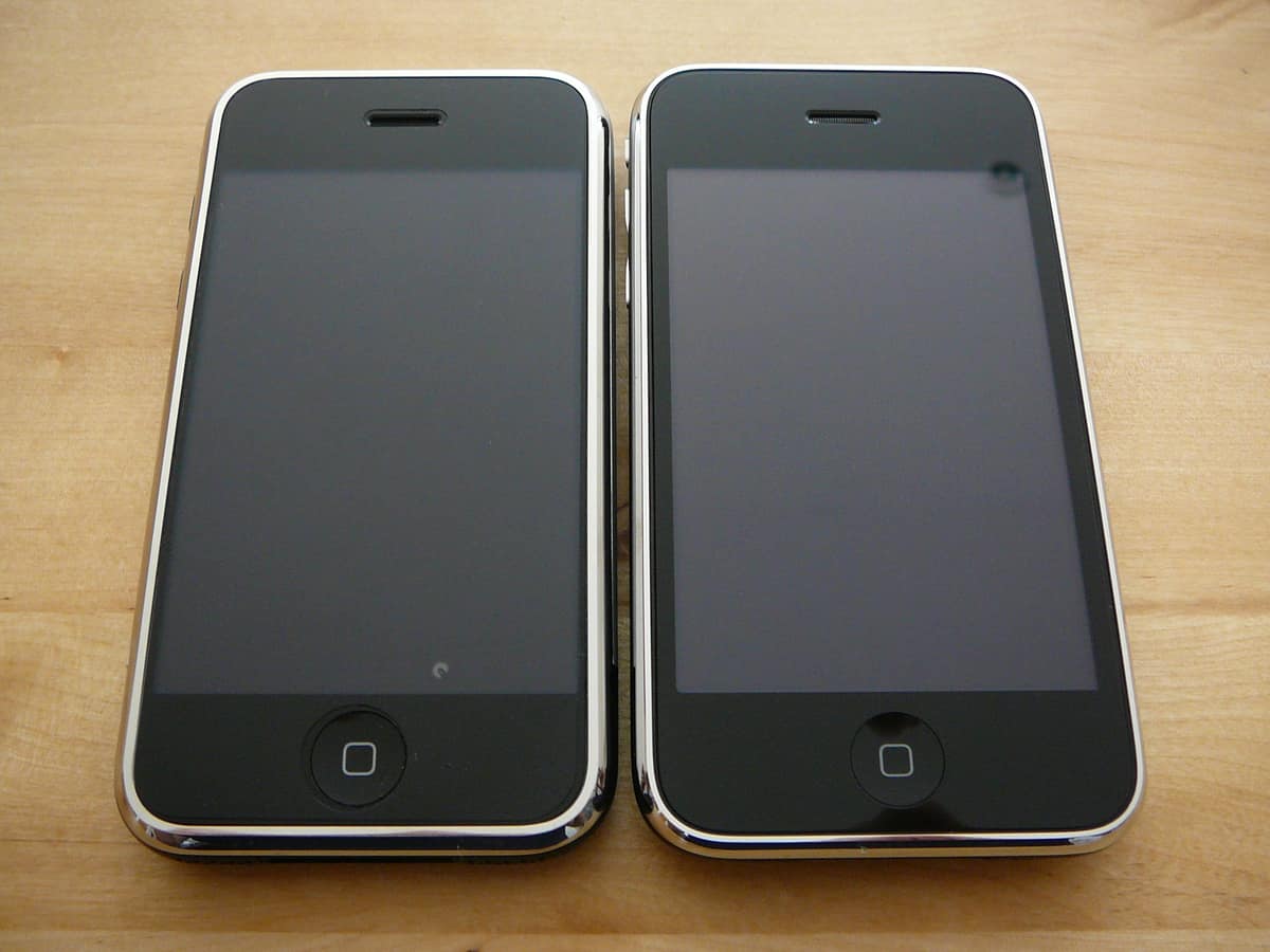 An iPhone 3G next to the original iPhone, both powered on and showing their home screens, photographed July 11, 2008.