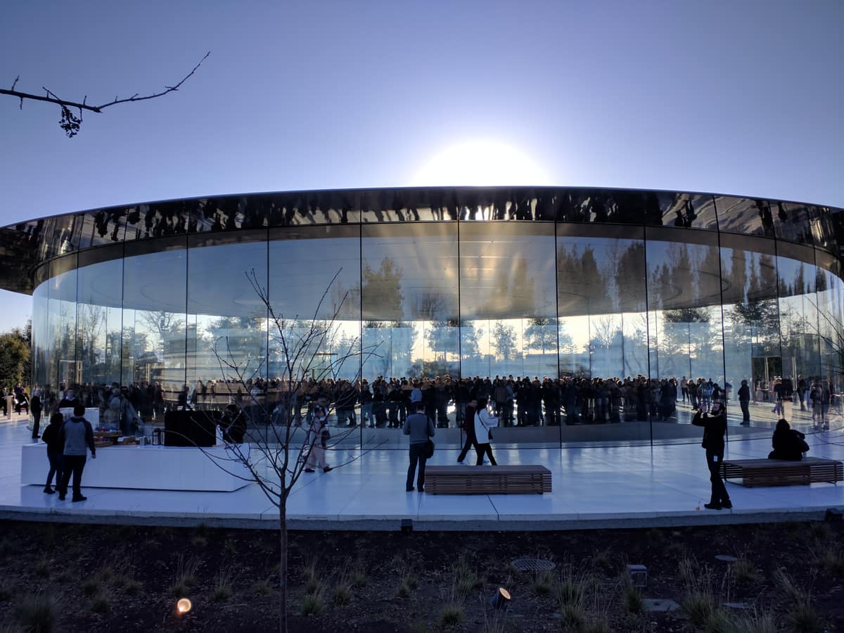 Exterior of the Steve Jobs Theater at Apple Park, a circular glass-walled pavilion topped by a metallic carbon-fiber roof
